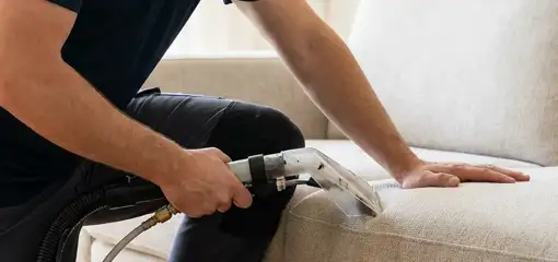 Professional upholstery cleaner deep-cleaning a fabric sofa with a handheld extraction tool, Portland, OR.